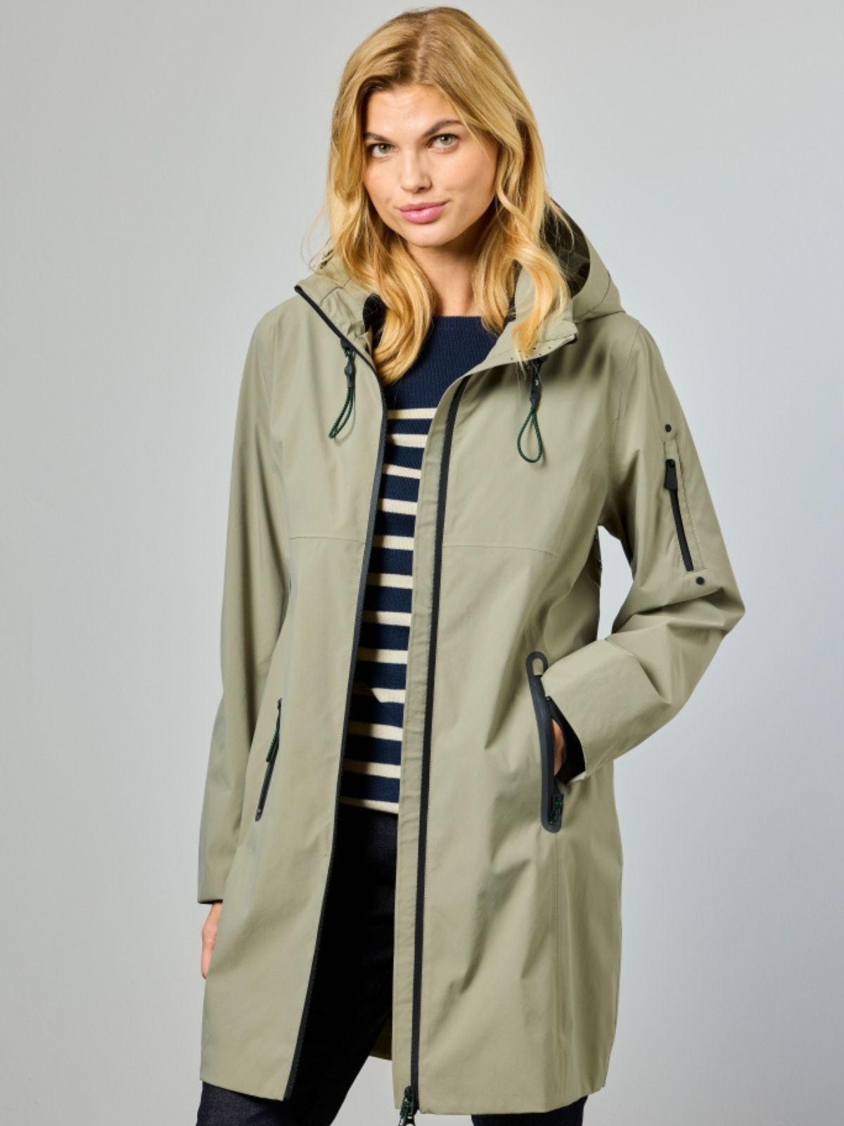 Nynne är en lång funktionsjacka för dam i light olive med modern silhuett och praktiska detaljer för övergångssäsongen.