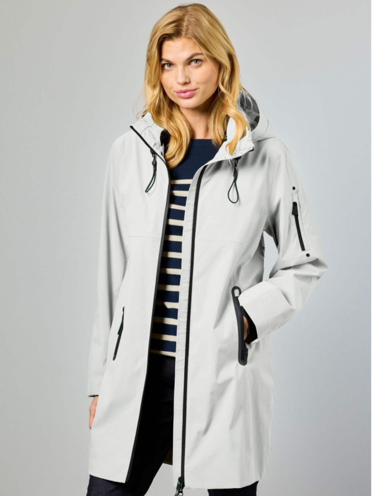 Nynne är en lång vårjacka för dam i ecru som skapar en elegant och balanserad silhuett.