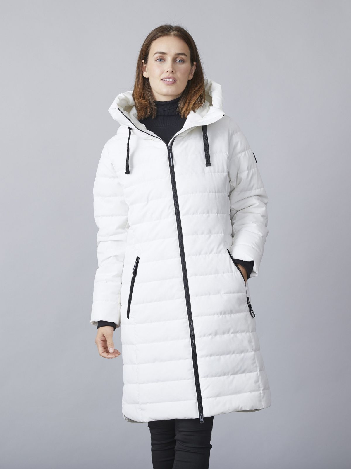 Modell iförd Kiki lång övergångsjacka för kvinnor i winter white med huva, dragkedja och quiltad design.
