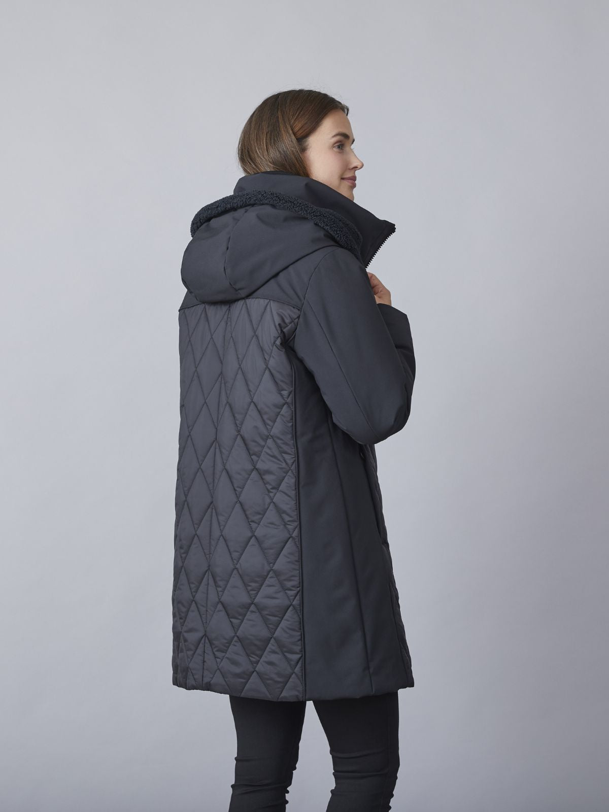 Modell iförd Kit övergångsjacka med huva för damer i svart quiltad design med teddy-detaljer och comfort fit.