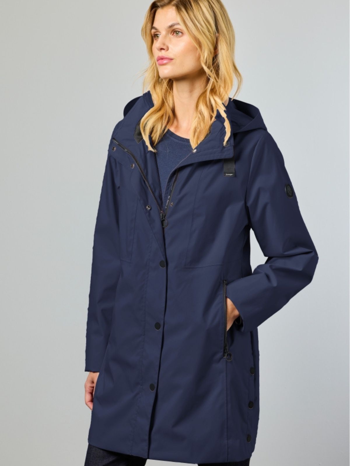 Noabelle är en lång övergångsjacka för dam i navy med elegant silhuett och extra skydd mot vindiga vårdagar.