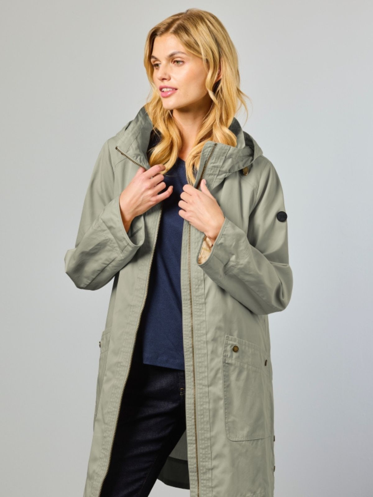 Nora är en lång vårjacka för dam i light olive med en modern silhuett och ett mjukt uttryck.